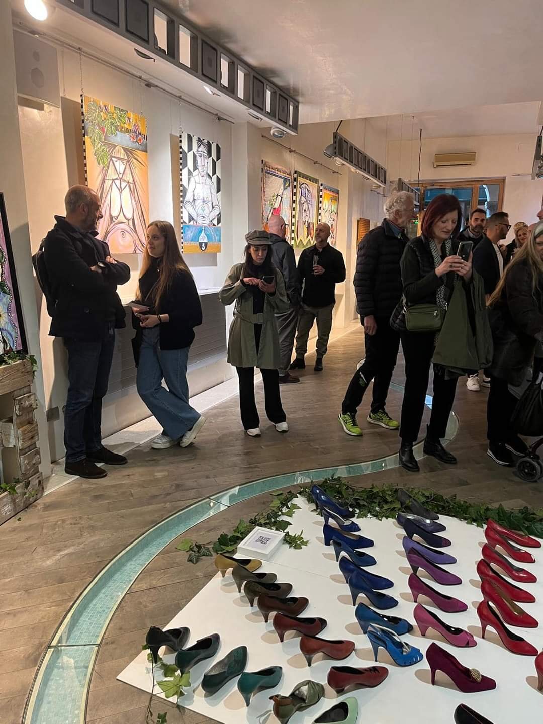 Il pubblico intorno all’installazione di scarpe durante il vernissage.