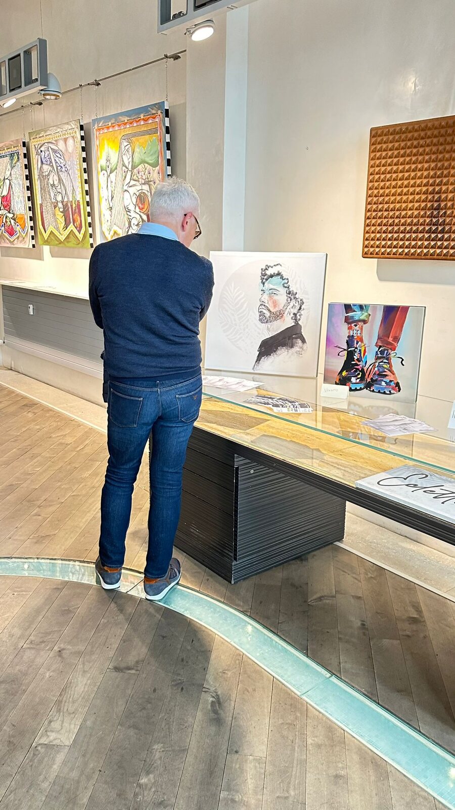 Un visitatore osserva da vicino una tela colorata appoggiata al bancone.