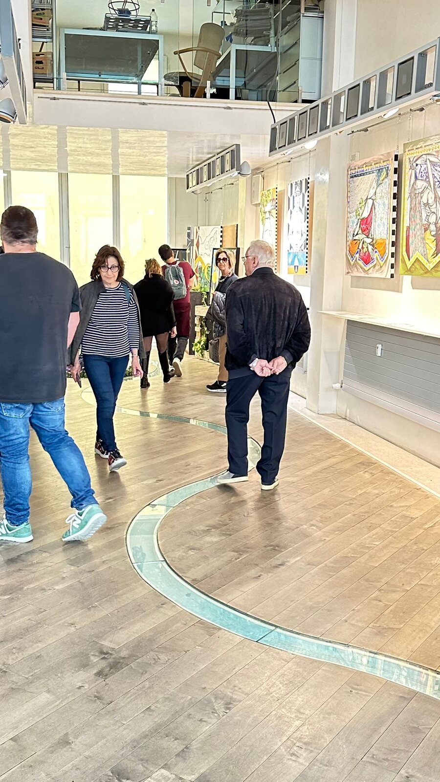 La sala allungata della galleria con le opere allineate sulla parete.