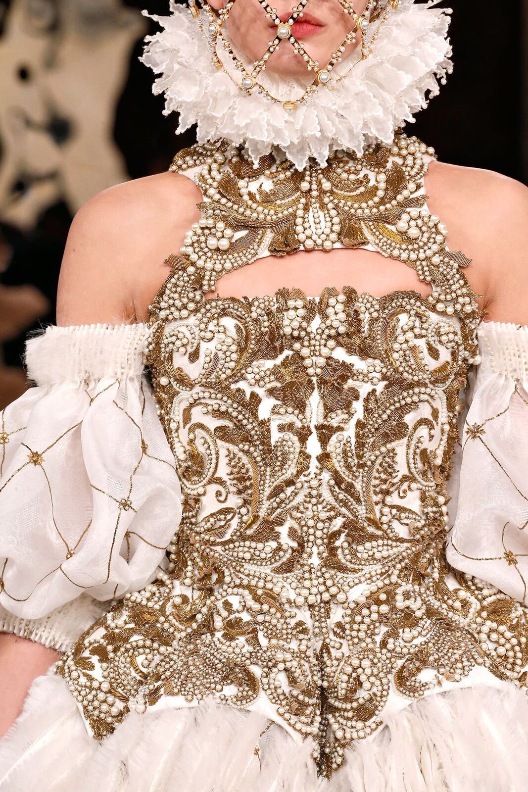 Dettaglio di un abito bianco con corpetto ricamato in oro e perle e collare a gorgiera di pizzo: il Rinascimento reinterpretato da Alexander McQueen, autunno-inverno 2013.