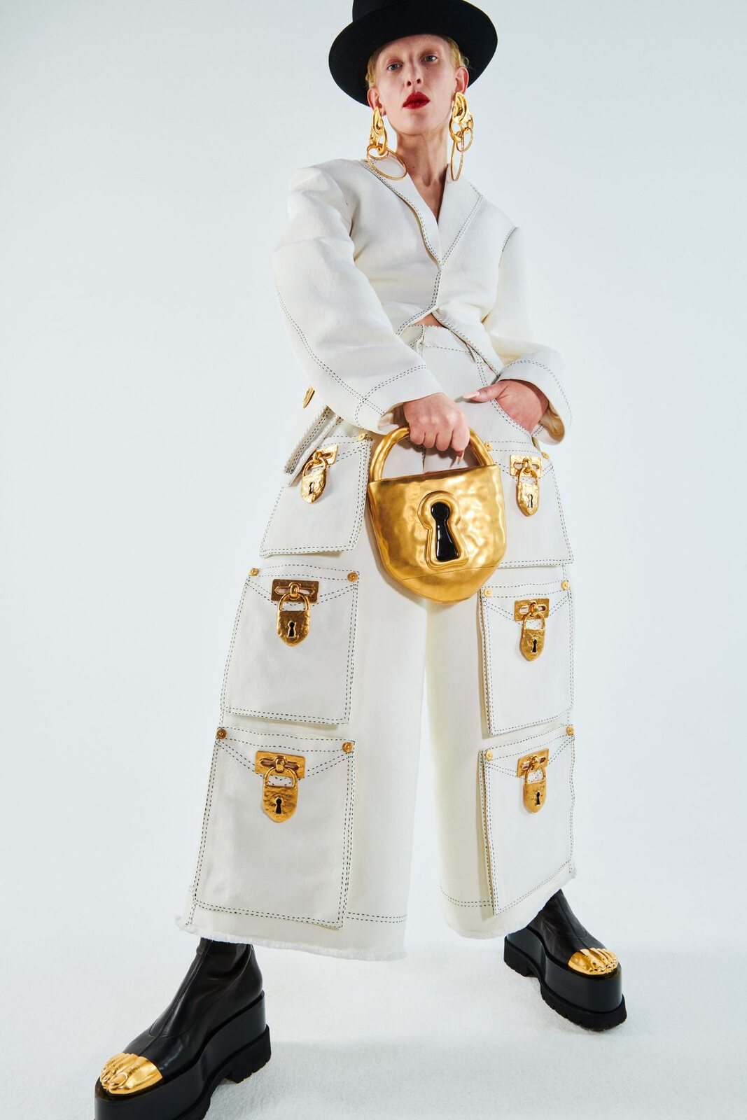 Completo bianco con grandi tasche chiuse da lucchetti dorati e borsa a forma di lucchetto: il surrealismo di Schiaparelli, primavera-estate 2021.