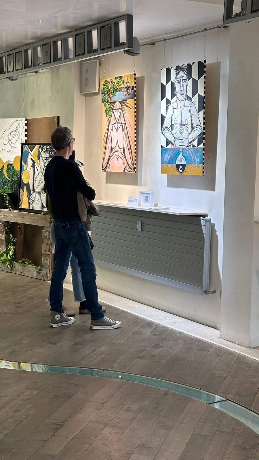 Una visitatrice guarda i dipinti appesi sopra il bancone.